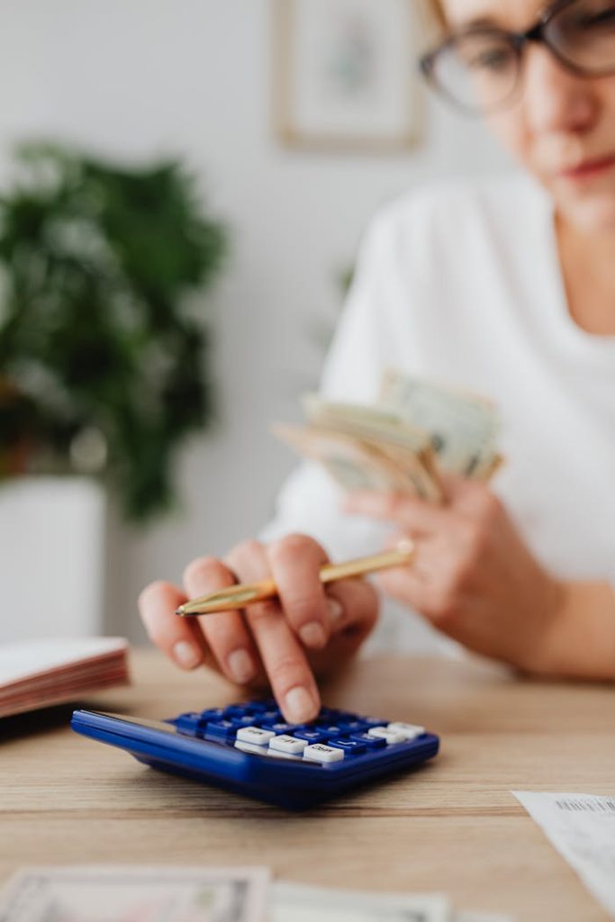 pexels photo 5900182 A woman uses a calculator and holds money, illustrating personal finance management.