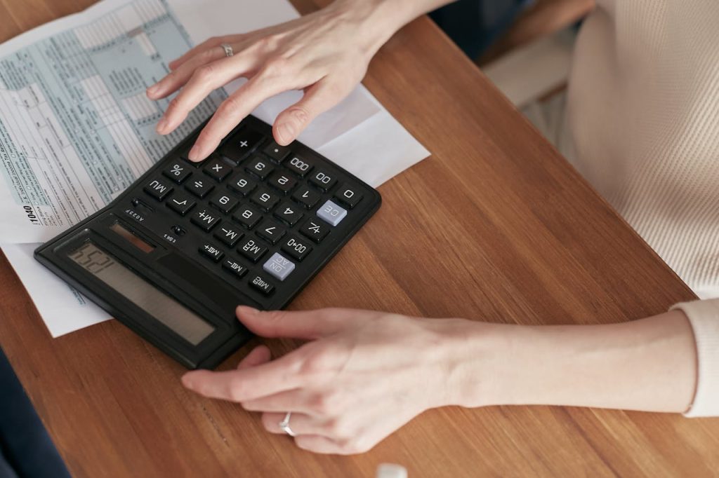 pexels photo 6963017 Close-up of a woman using a calculator and reviewing bills at home.